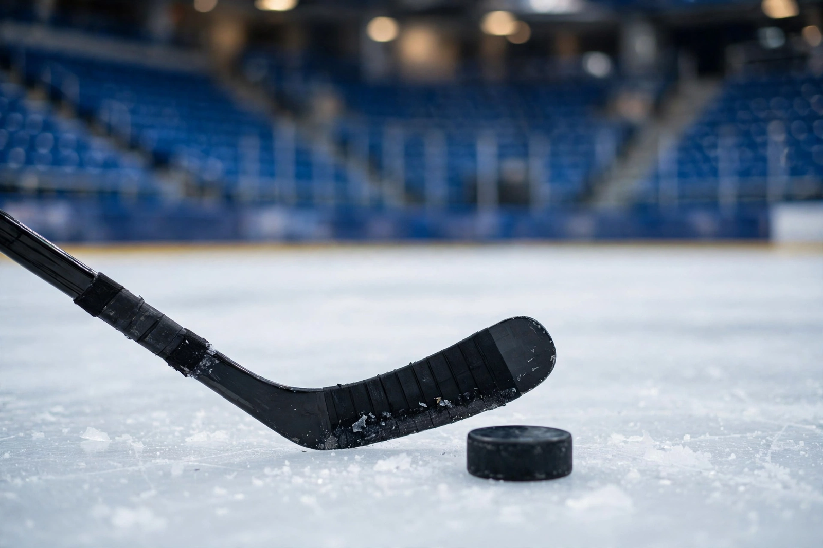 Hockey stick and puck on the ice in an empty arena